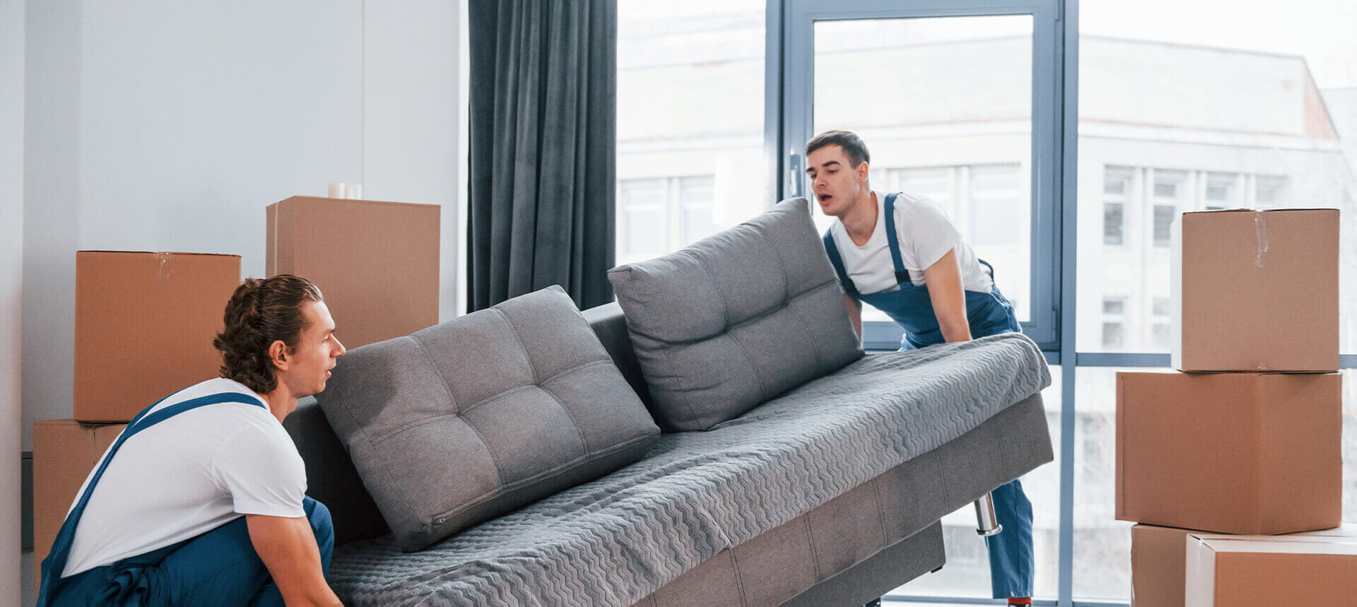 Bild zeigt einen Mitarbeiter, der ein Sofa trägt